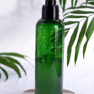 Plastic green bottle with natural lotion for clean skin on a white textile background wit green